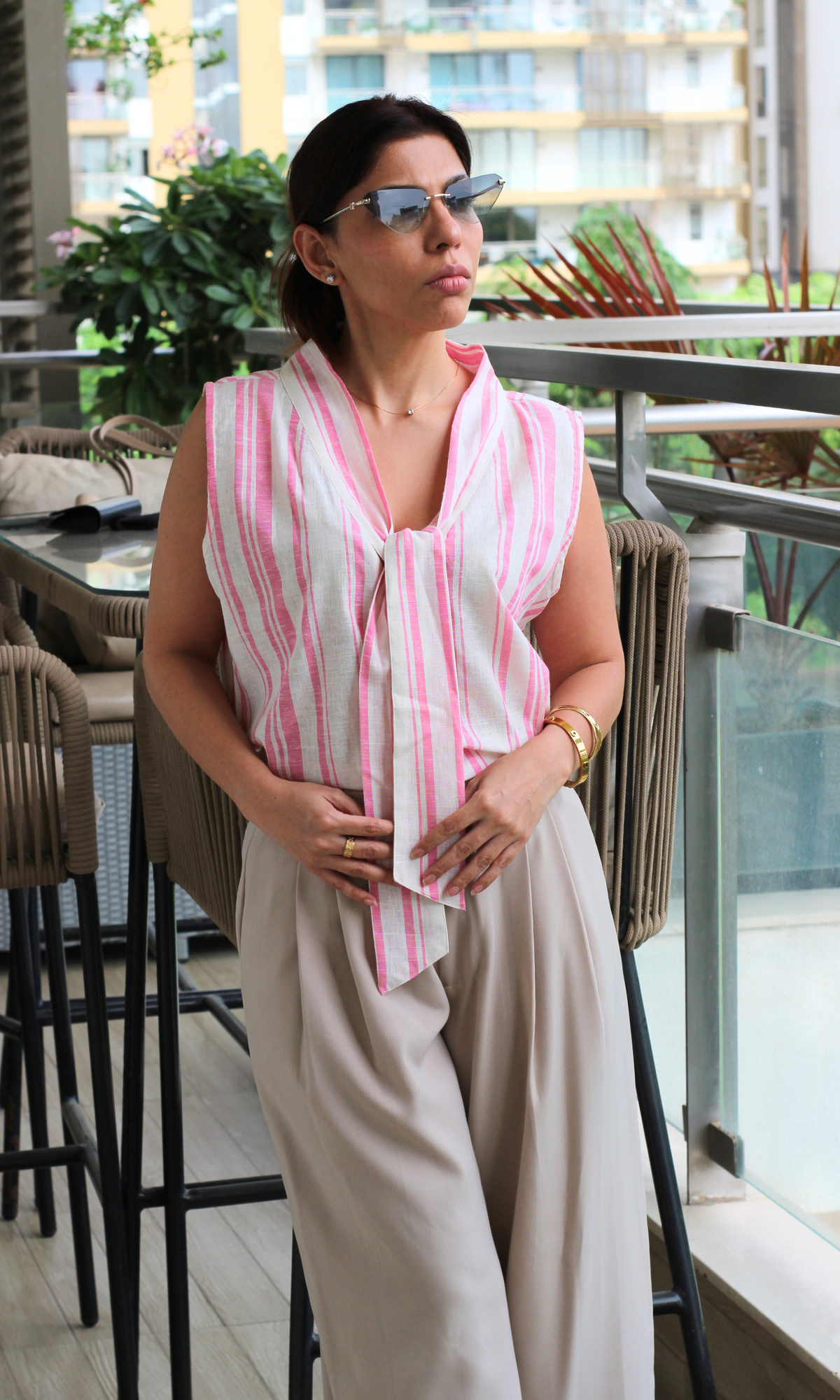 Relaxed daytime look with a cotton tie-front top in pink and white stripes, styled with wide-leg trousers in a soft neutral tone.
