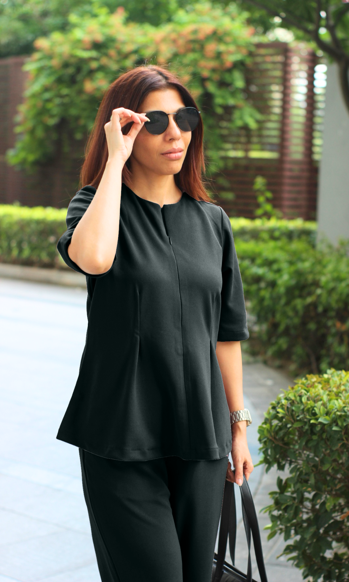 Elegant black two-piece outfit with a fitted waist peplum blouse and relaxed trousers, perfect for a modern workwear look.
