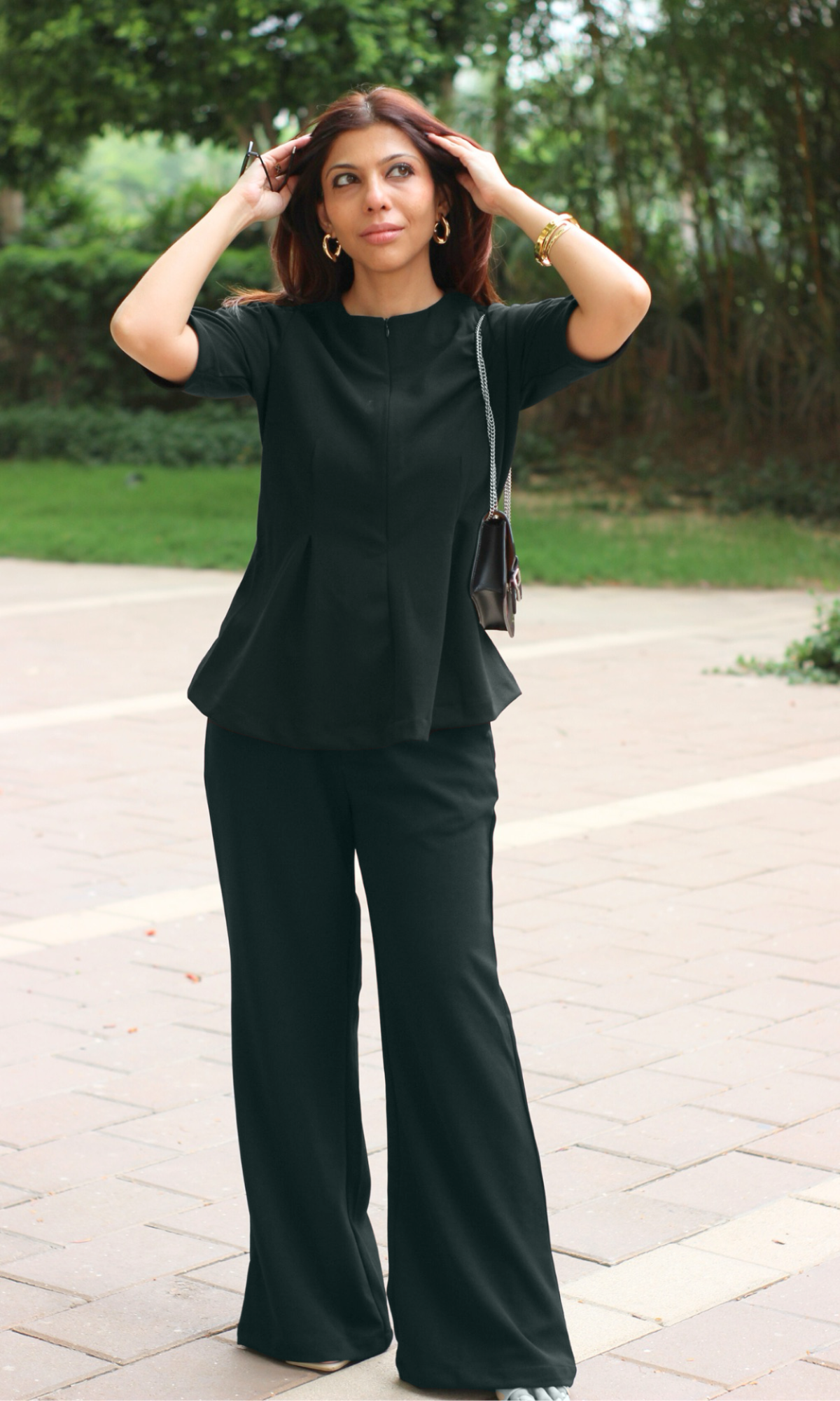Woman wearing a black peplum top paired with matching black wide-leg trousers and minimal accessories for a chic monochrome look.