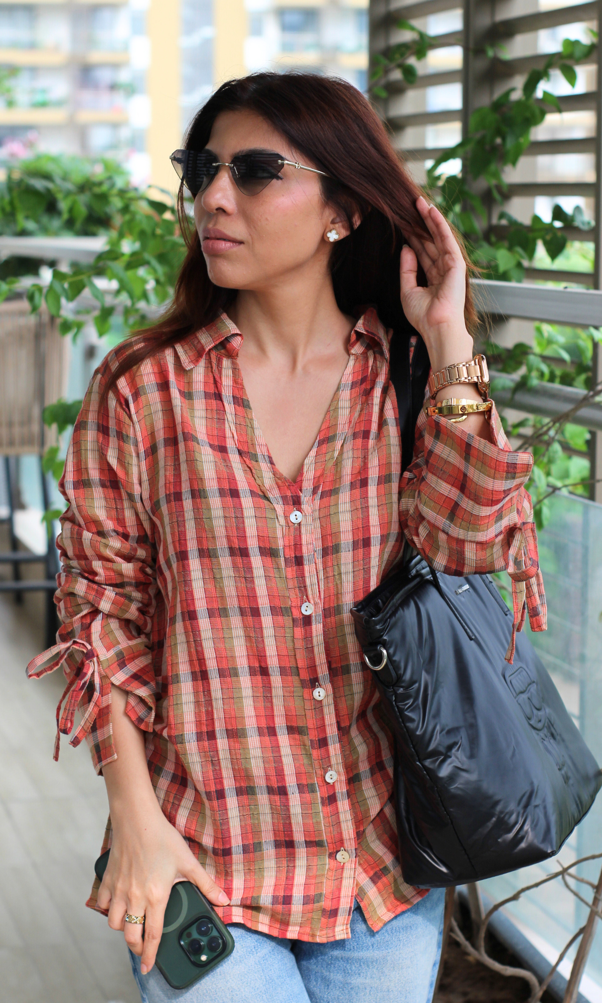 Rust checkered shirt with gathered sleeves, paired with denim and a black puffer bag.