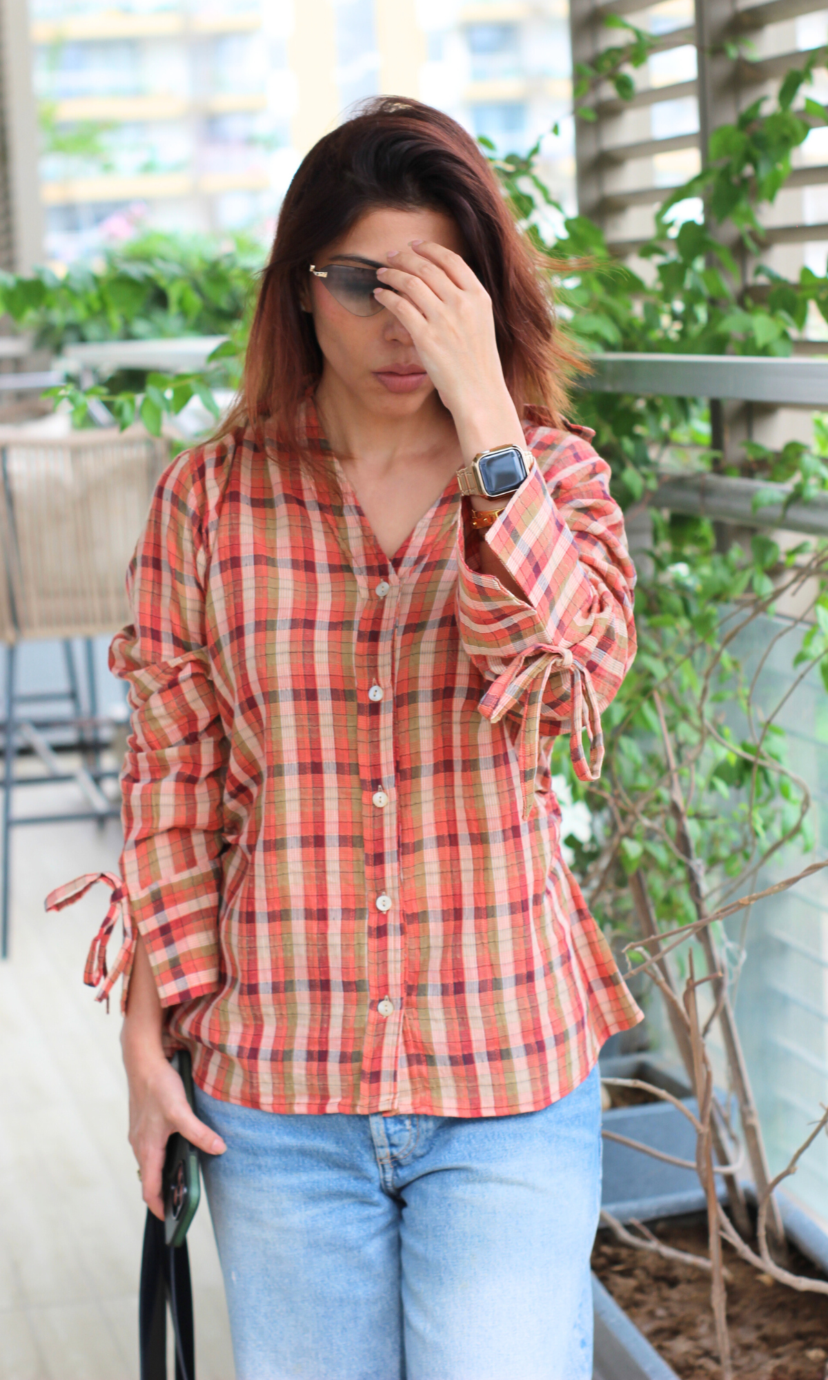 Checked button-down shirt with ruched sleeves and tie details, paired with blue jeans.