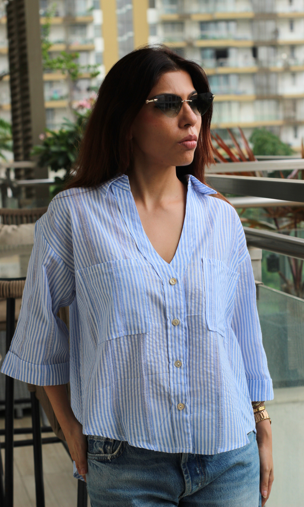 Blue striped shirt with front pockets, styled with denim and sunglasses.