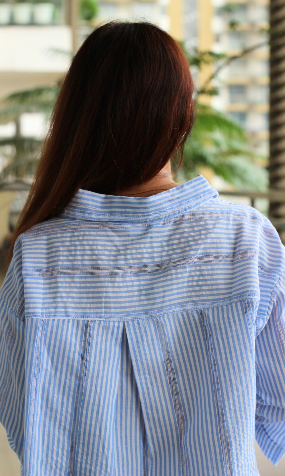 Back view of a woman in a blue and white striped shirt.