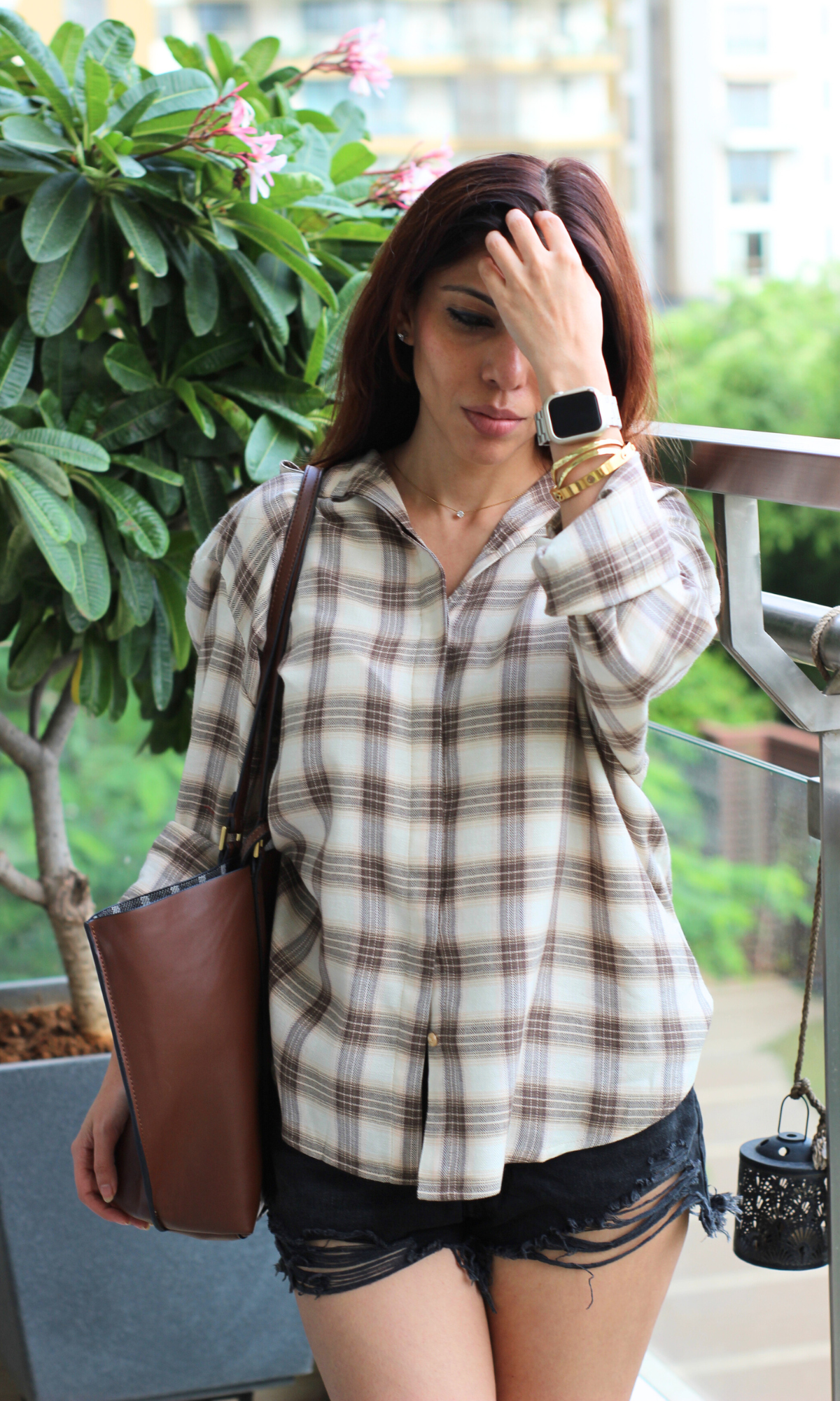 Lightweight checkered button-up shirt in neutral tones styled with black distressed shorts and a casual tote bag.