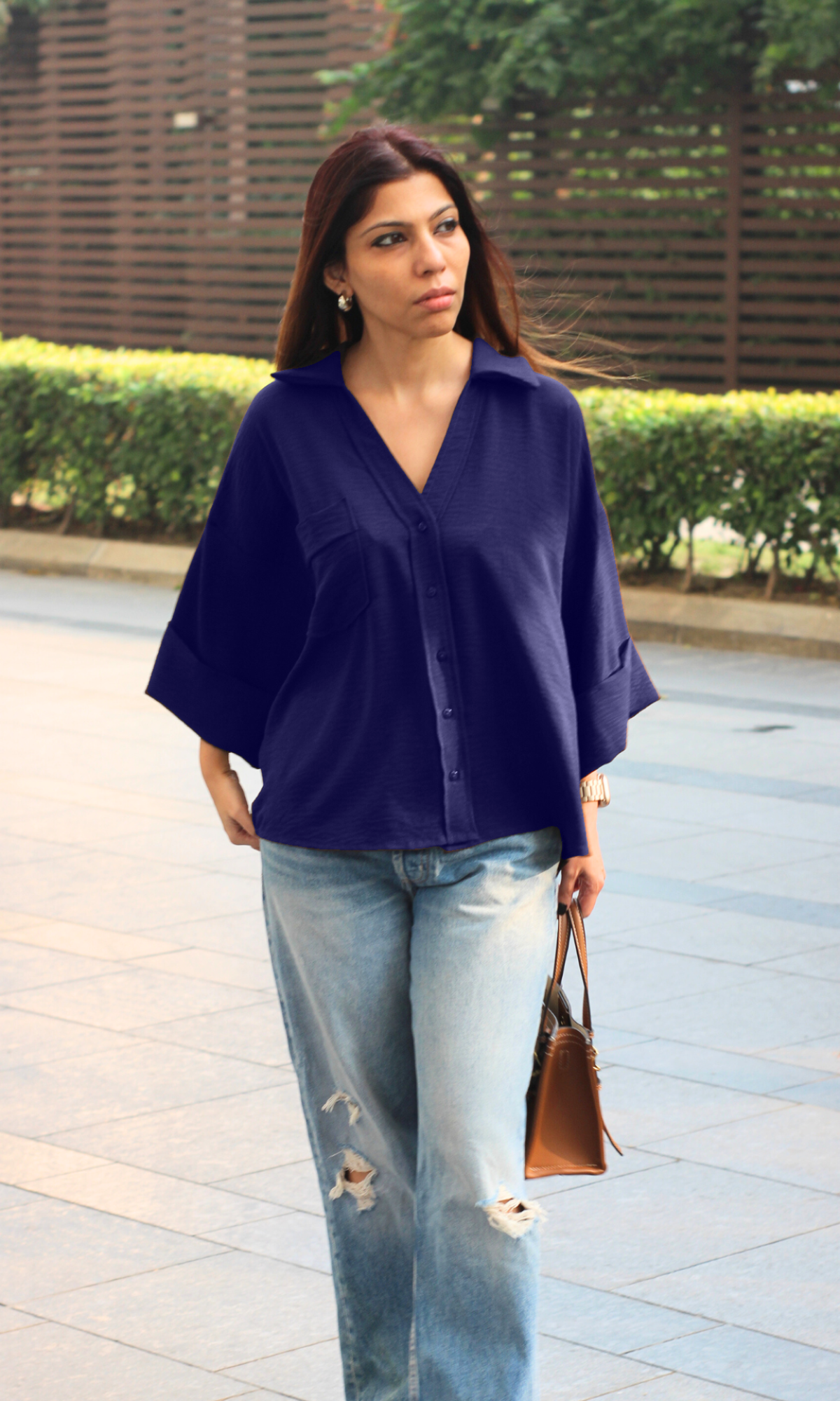 Chic pastel outfit featuring the Violet Flowing Shirt tucked into beige tailored pants, and carrying tan bag.