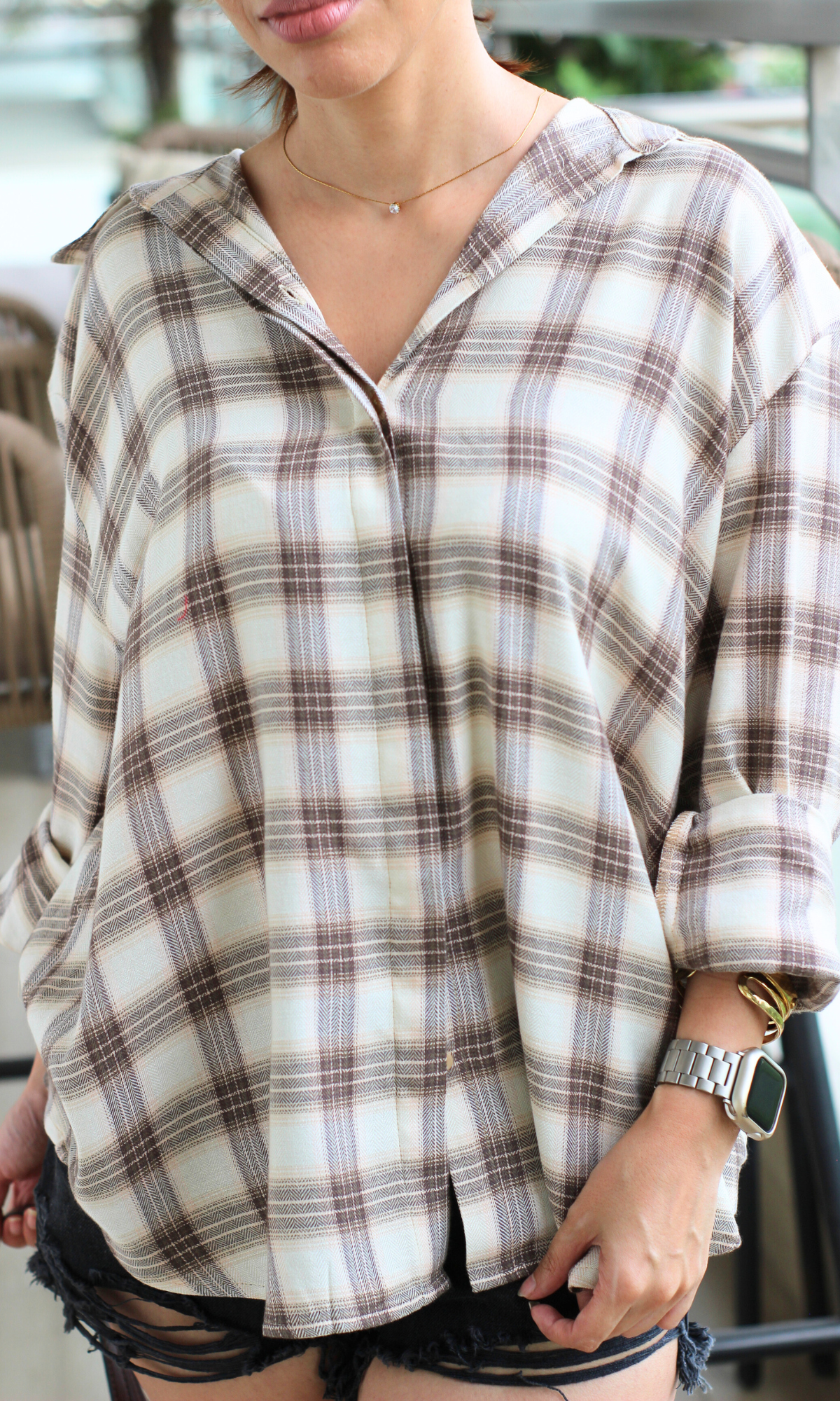 Front view of a beige checkered shirt in a relaxed fit paired with ripped black denim shorts, perfect for a laid-back summer look.