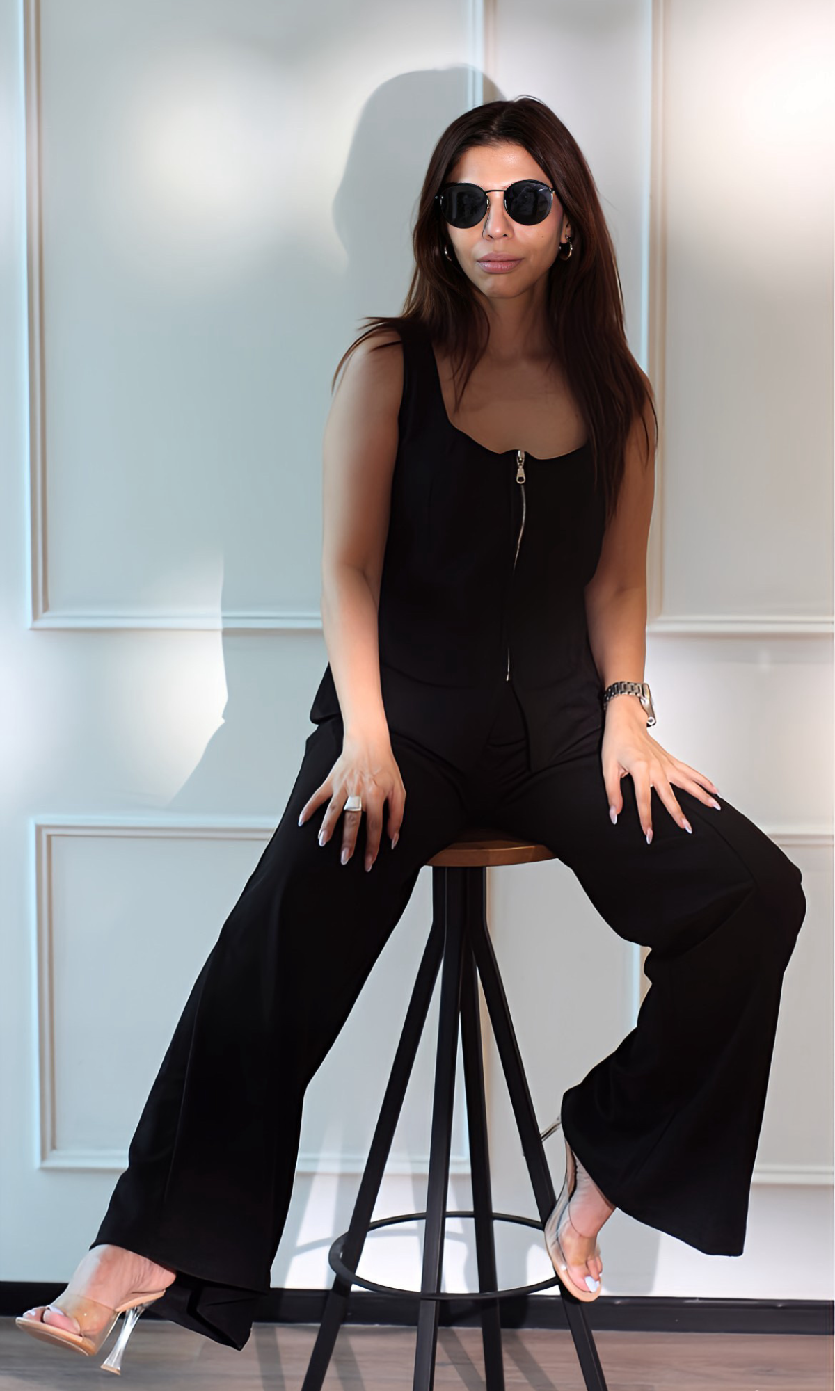 Sitting pose in the Noir Zip Detail Top and Flared Pants Co-ord featuring a structured zippered top and wide-leg black trousers draped elegantly.