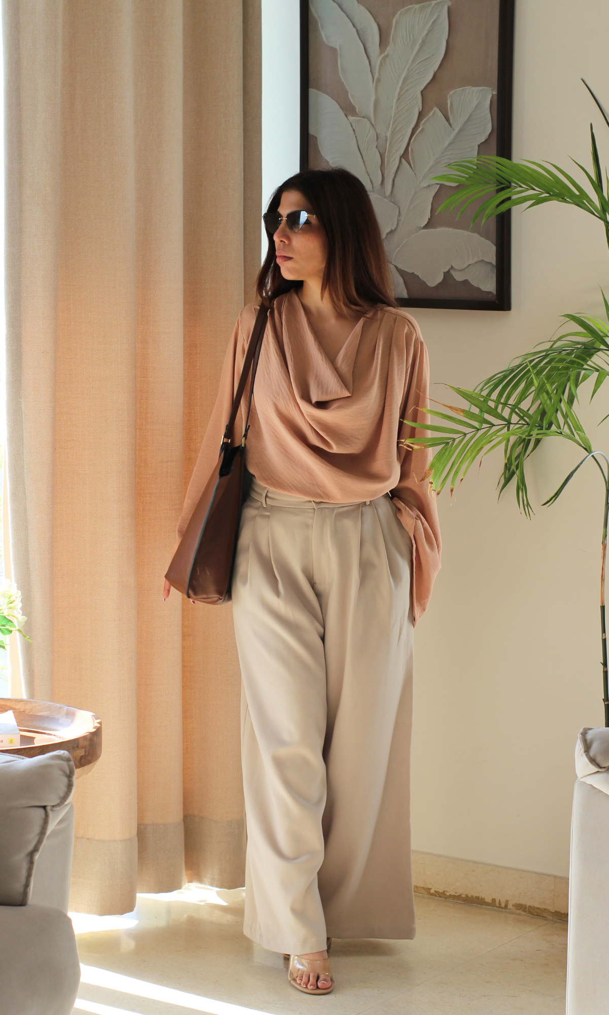 Fashionable dusky pink top featuring a cowl neckline and elegant slit sleeves, paired with casual bottoms.