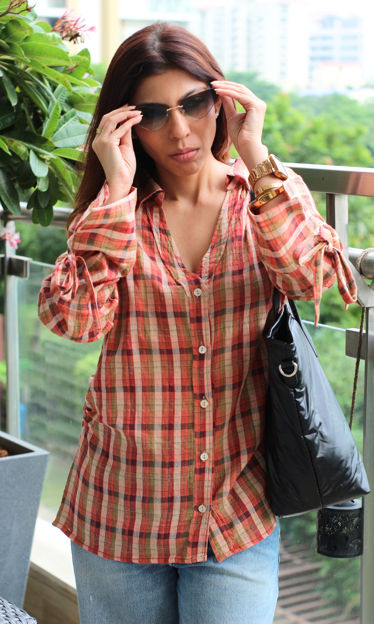 Rust-orange plaid shirt with tie-up sleeves, styled with jeans and sunglasses.