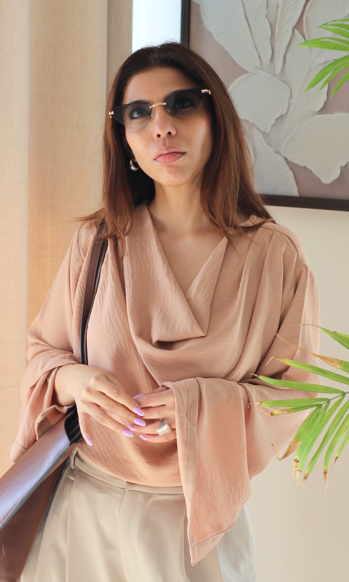 Fashionable dusky pink top featuring a cowl neckline and elegant slit sleeves, paired with casual bottoms.