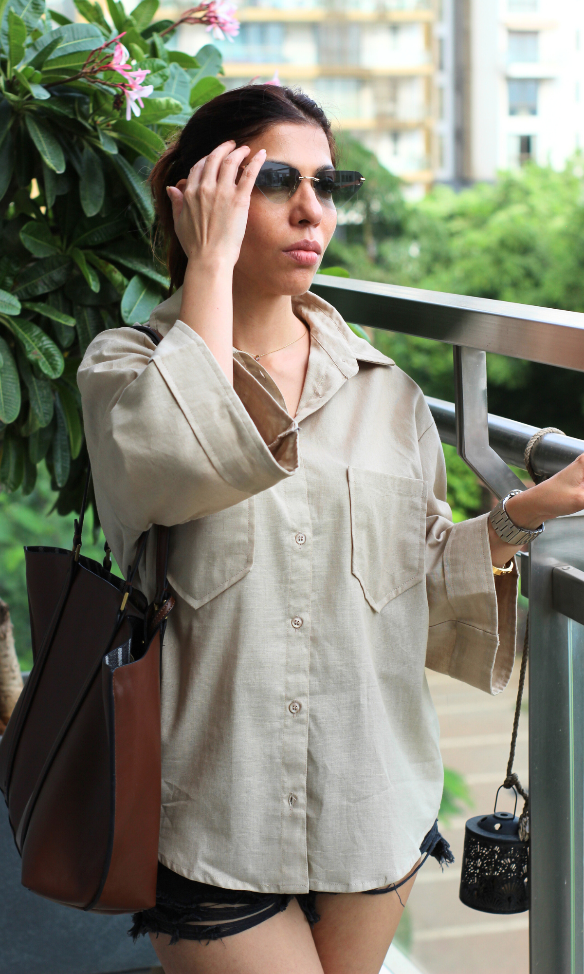 Effortless off-duty look with a relaxed beige button-up shirt and distressed black denim shorts, styled for a chic summer vibe.