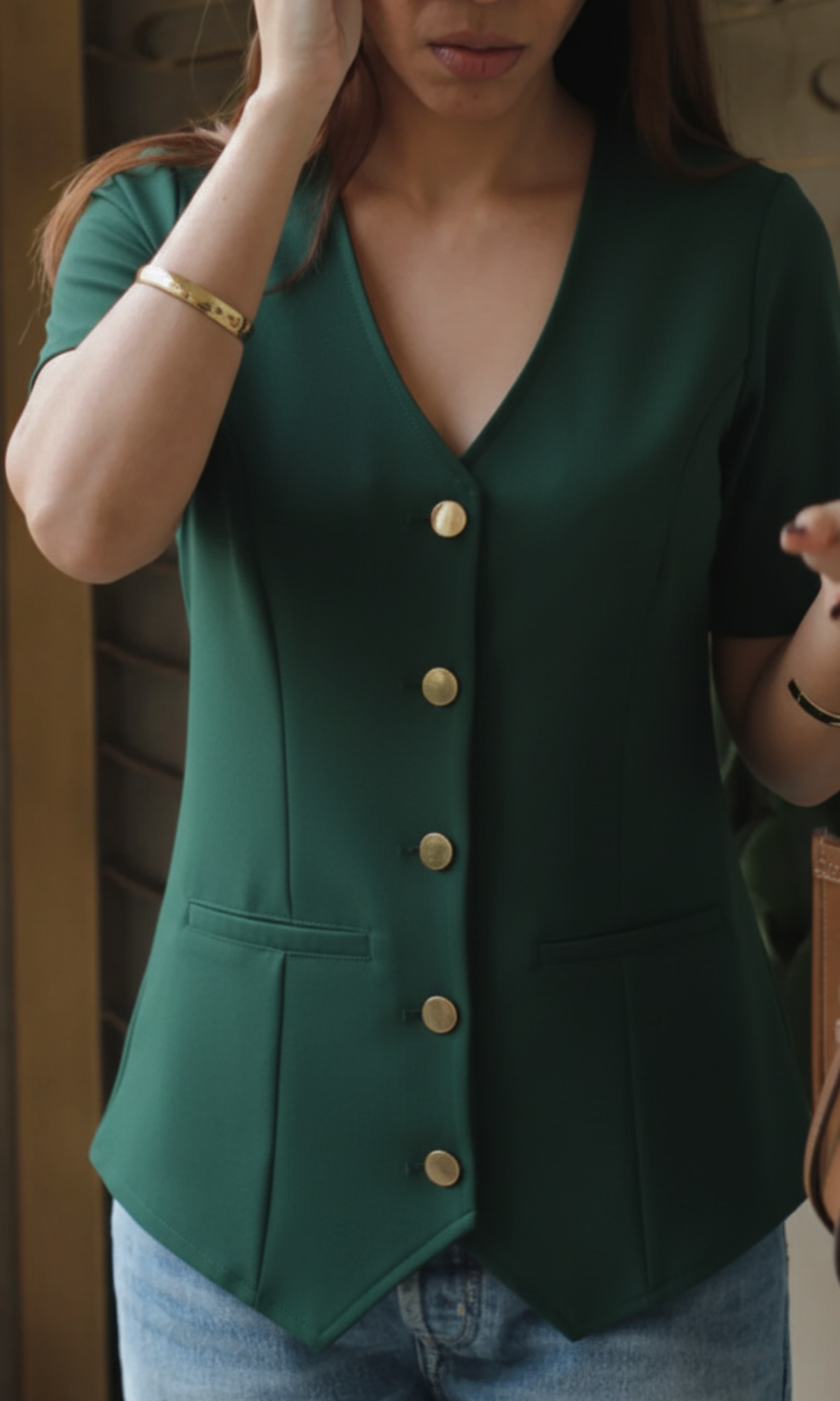 Close-up of deep green sleeved metallic buttoned waistcoat showing textured fabric and button detail