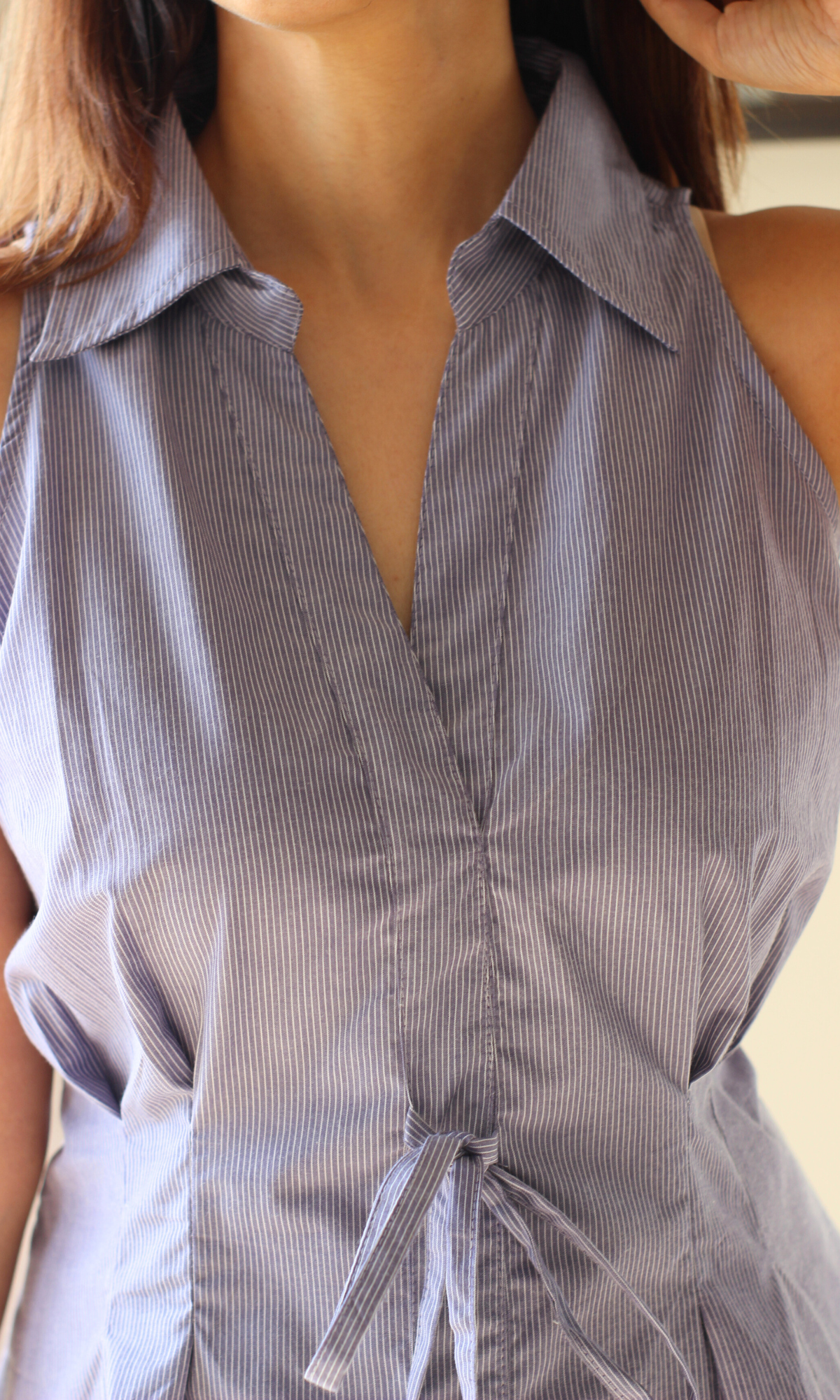 Woman wearing a purple stripe blouse with waist tie accent and soft draping.