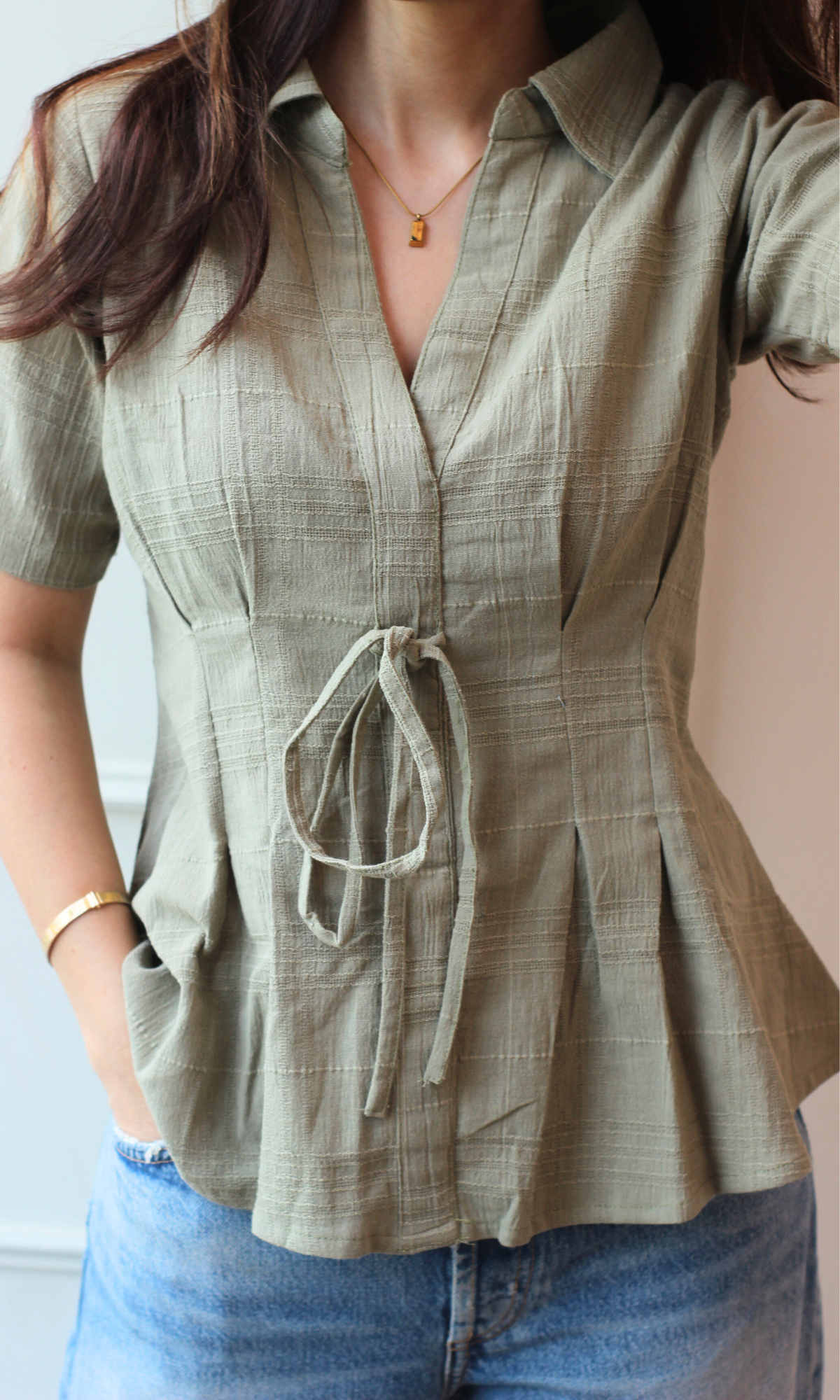 Chic olive top featuring a tailored fit, collar, V-neckline, and adjustable tie at the waist.