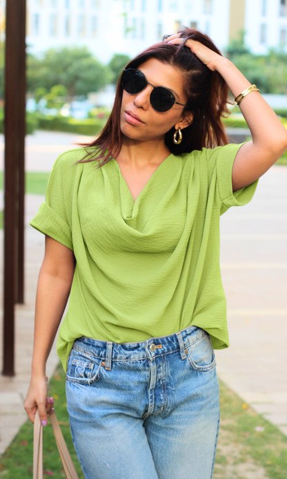 Flowing lime green top with draped cowl neck design and relaxed hemline.