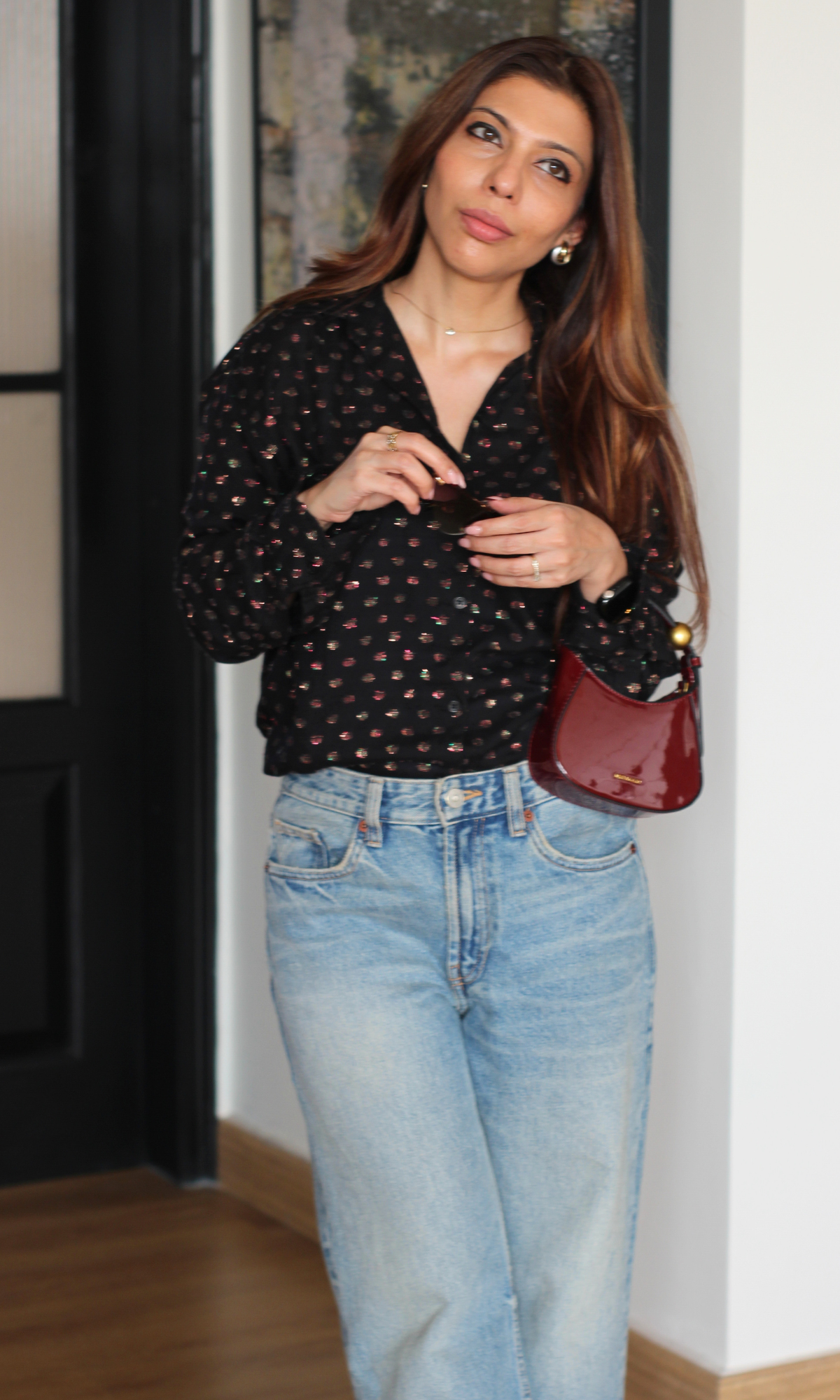 Woman wearing black lurex flowing shirt with long sleeves and soft drape.