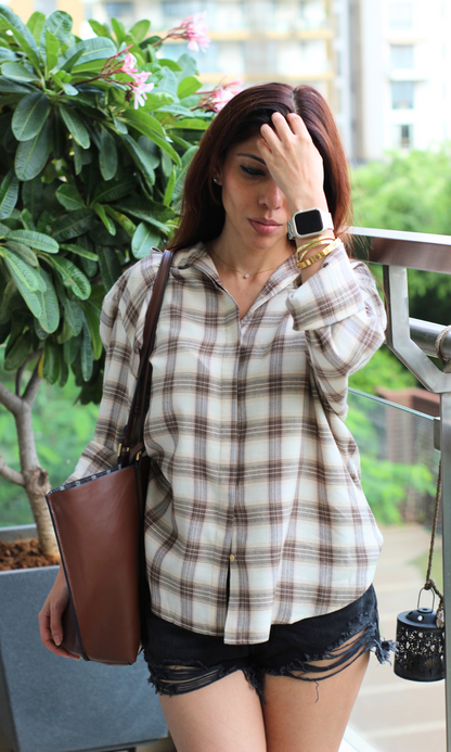 Lightweight checkered button-up shirt in neutral tones styled with black distressed shorts and a casual tote bag.