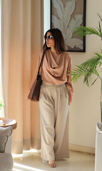 Fashionable dusky pink top featuring a cowl neckline and elegant slit sleeves, paired with casual bottoms.